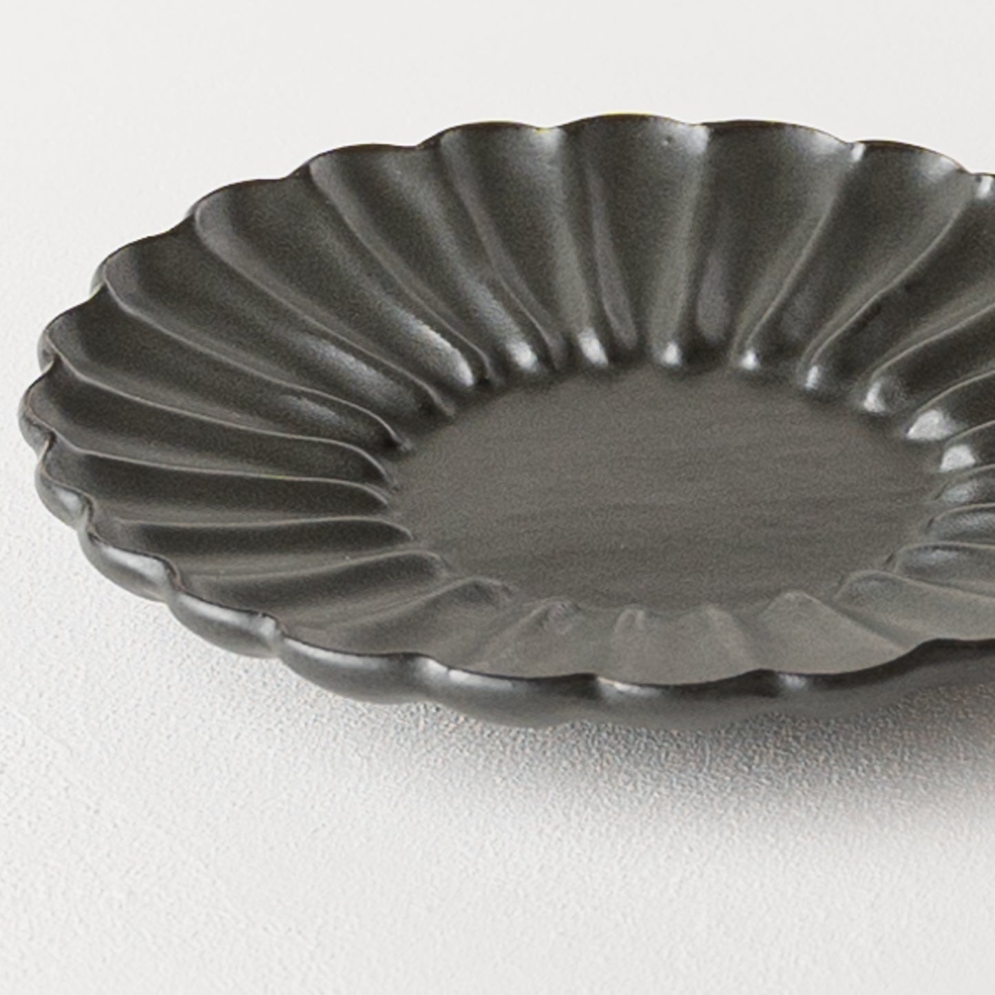 グレーがかった黒にあたたかみを感じるyoshida potteryの輪花皿