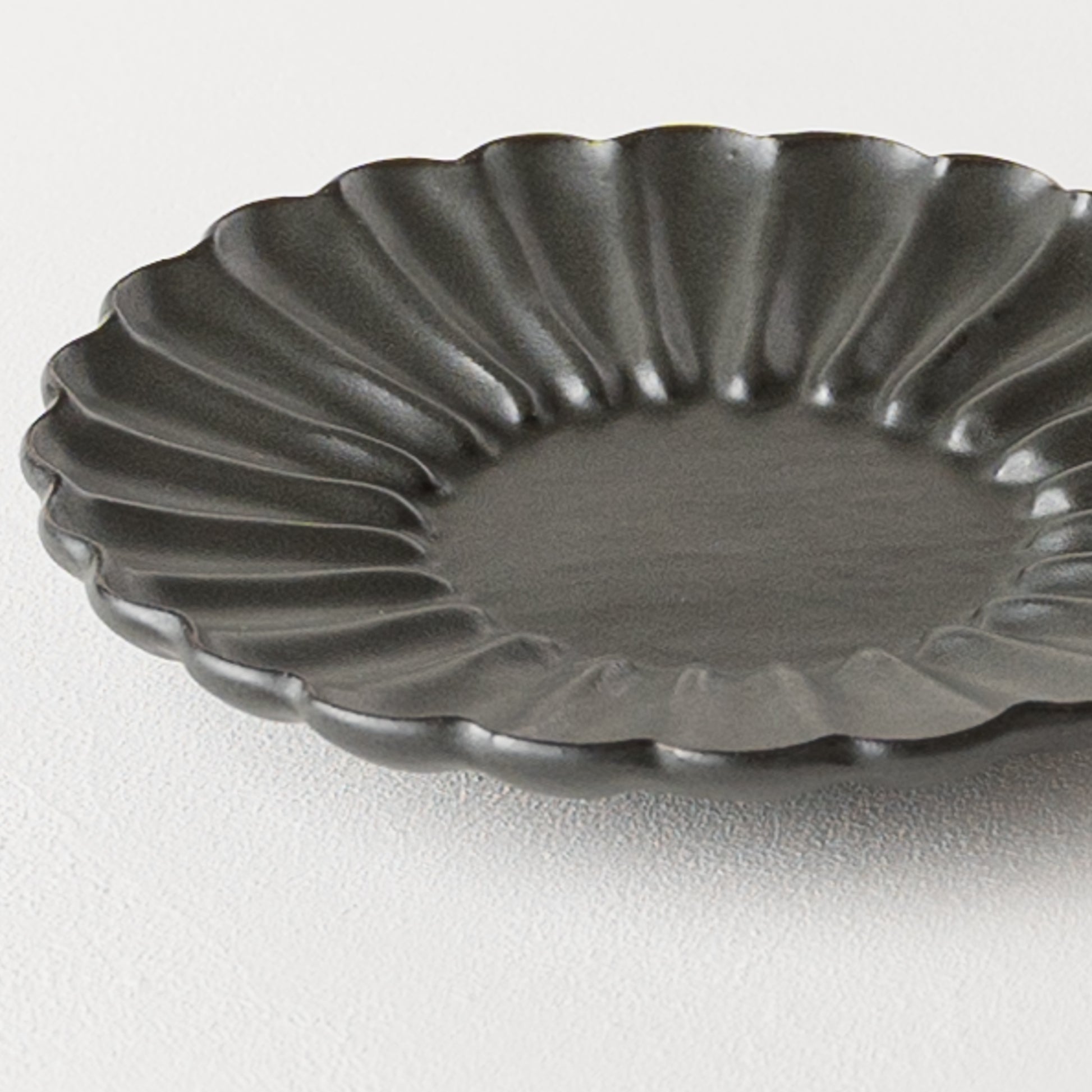 グレーがかった黒にあたたかみを感じるyoshida potteryの輪花皿